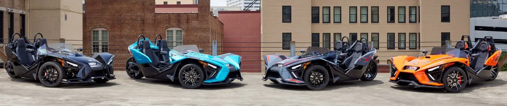 4 different colored slingshots sown on a parking garage roof. Polaris Slingshot Rental from Island Jet Skis in Freeport Long Island NY.